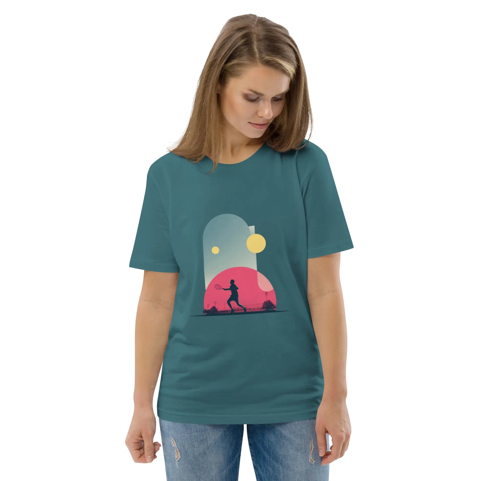 T-shirt adulte vert-bleu en coton bio "Smash Chromatique" avec illustration d’un joueur de tennis en action, couleurs vives rose, bleu et jaune, style graphique dynamique évoquant mouvement et fluidité. Vue de face. La femme qui porte le t-shirt regarde vers le bas.