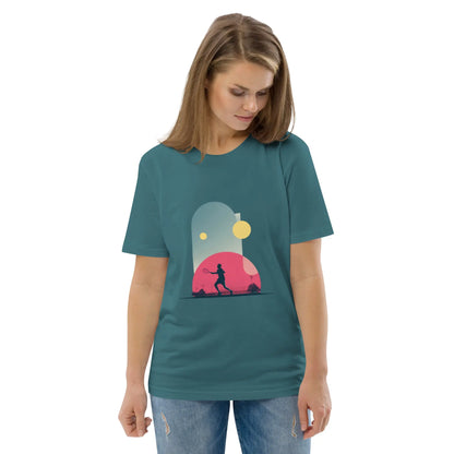 T-shirt adulte vert-bleu en coton bio "Smash Chromatique" avec illustration d’un joueur de tennis en action, couleurs vives rose, bleu et jaune, style graphique dynamique évoquant mouvement et fluidité. Vue de face. La femme qui porte le t-shirt regarde vers le bas.